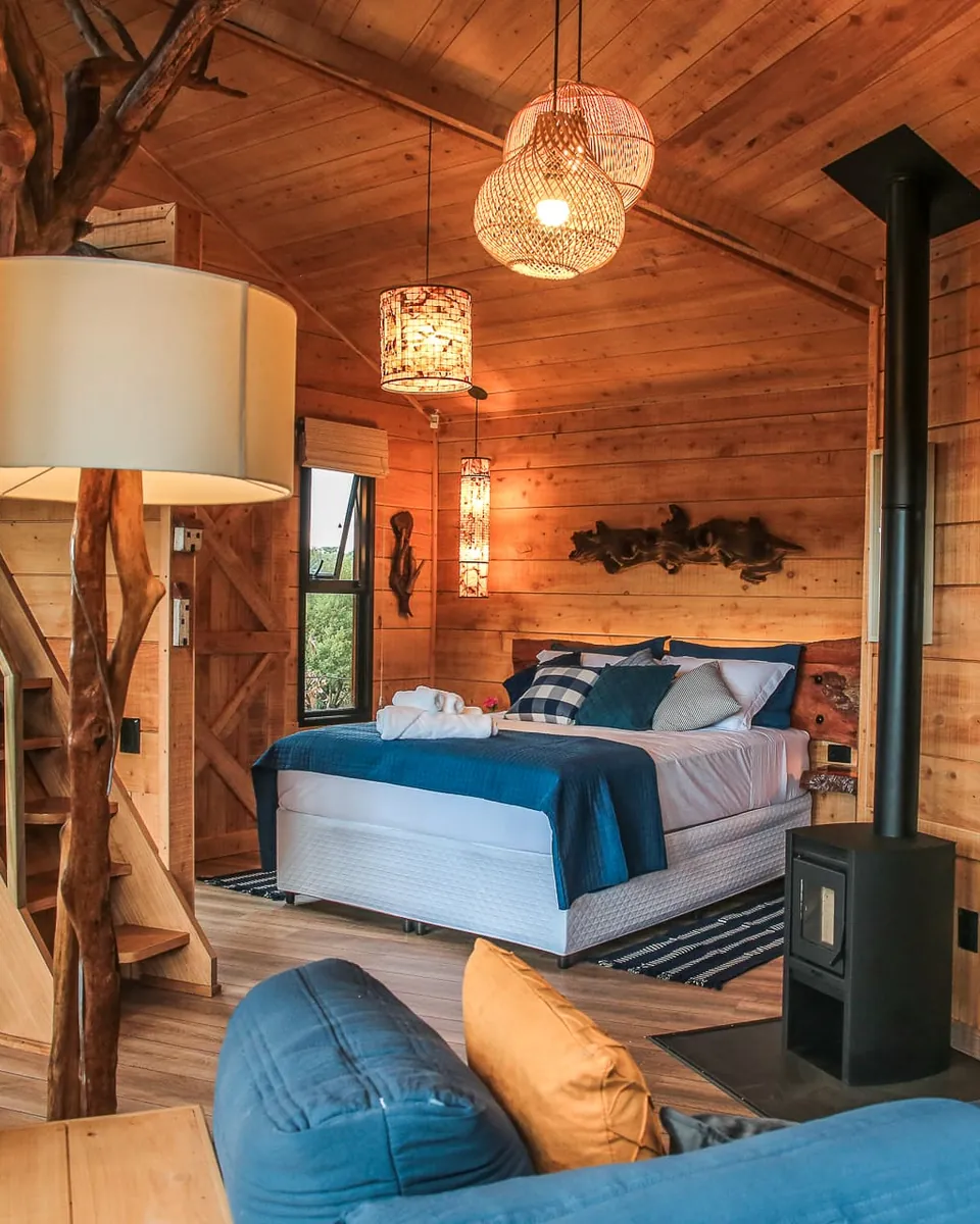 Quarto de madeira com cama de casal e lareira a lenha